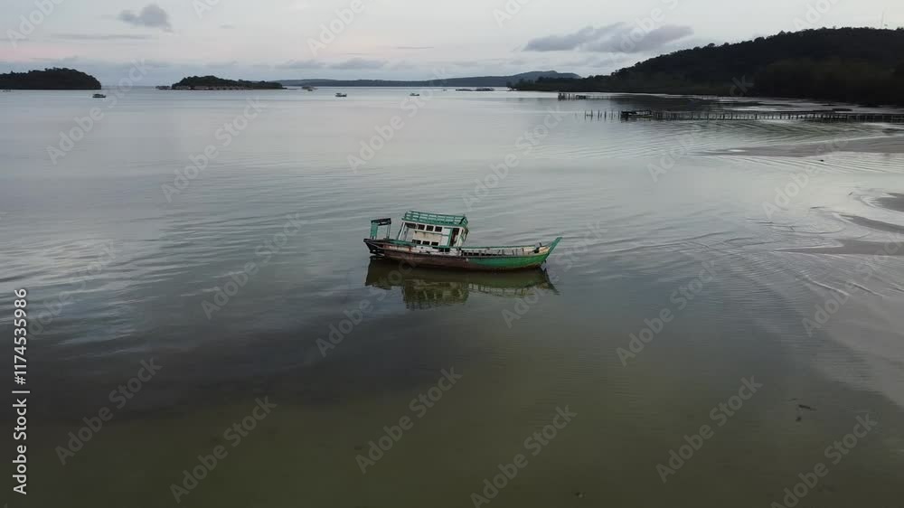 Drone rotating around rustic abandoned boat in the sea with lush green vegetation around