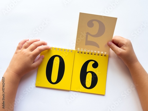 Child flipping calendar pages to change date on desk photo