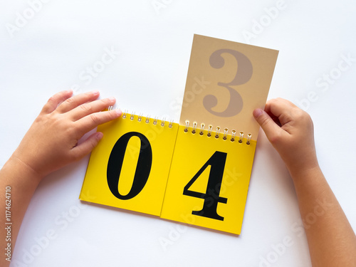 Childs hands turning pages on educational flip calendar with bold numbers