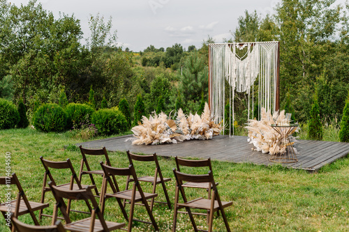 Decorated wedding arch and wooden chairs at wedding ceremony photo