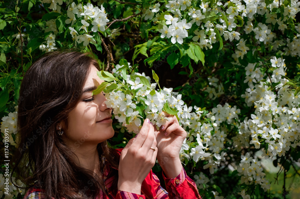 Russian brunette woman enjoying the scent of blooming apple tree blossoms on a spring day. The scene highlights her natural beauty and the freshness of spring Russian brunette woman enjoying the scent of blooming apple tree blossoms on a spring day. The scene highlights her natural beauty and the freshness of spring