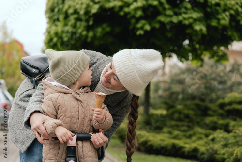 Mother supports her daughter while she learns to ride a scooter outdoors, close-up. The concept of solo parenting and raising children.