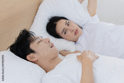 Portrait of a man snoring while a woman blocking her ears pillow  photo