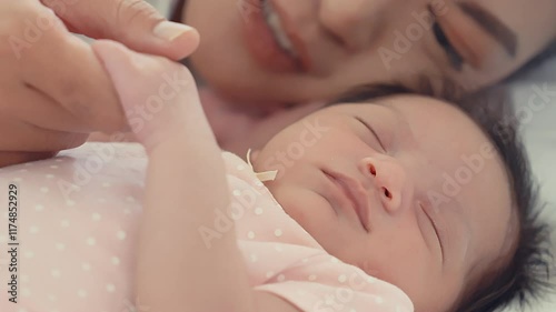 A heartfelt scene of a mother lovingly holding the hand of her peacefully sleeping newborn baby. The close-up composition captures the intimate bond and warmth between parent and child.