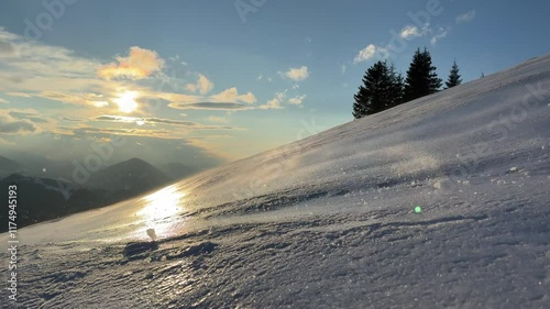Strong wind blowing over frozen snow against sunset light