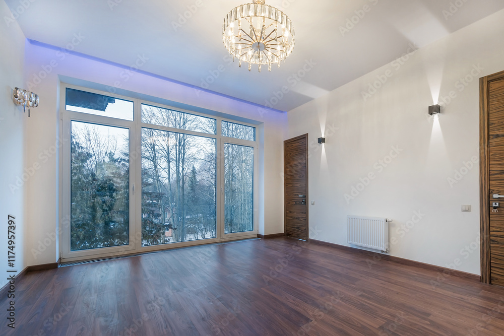 Obraz premium Panoramic window in the room of a luxurious country mansion with a picturesque view of .the winter landscape. A room with a parquet floor, a luxurious chandelier, unfurnished.