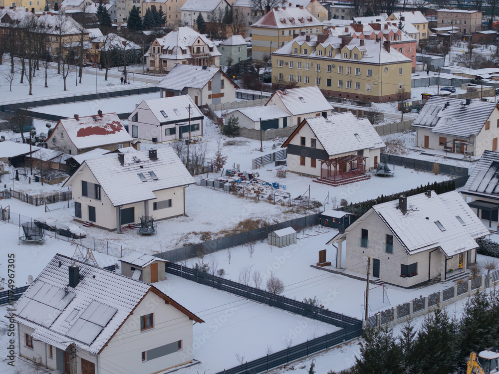 Fototapeta premium Streets and roofs of houses are covered with snow after an overnight snowfall caused by a passing cold atmospheric front on a winter morning.