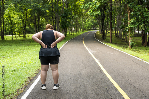 Asian fat fitness woman feeling back pain during work out in public park
