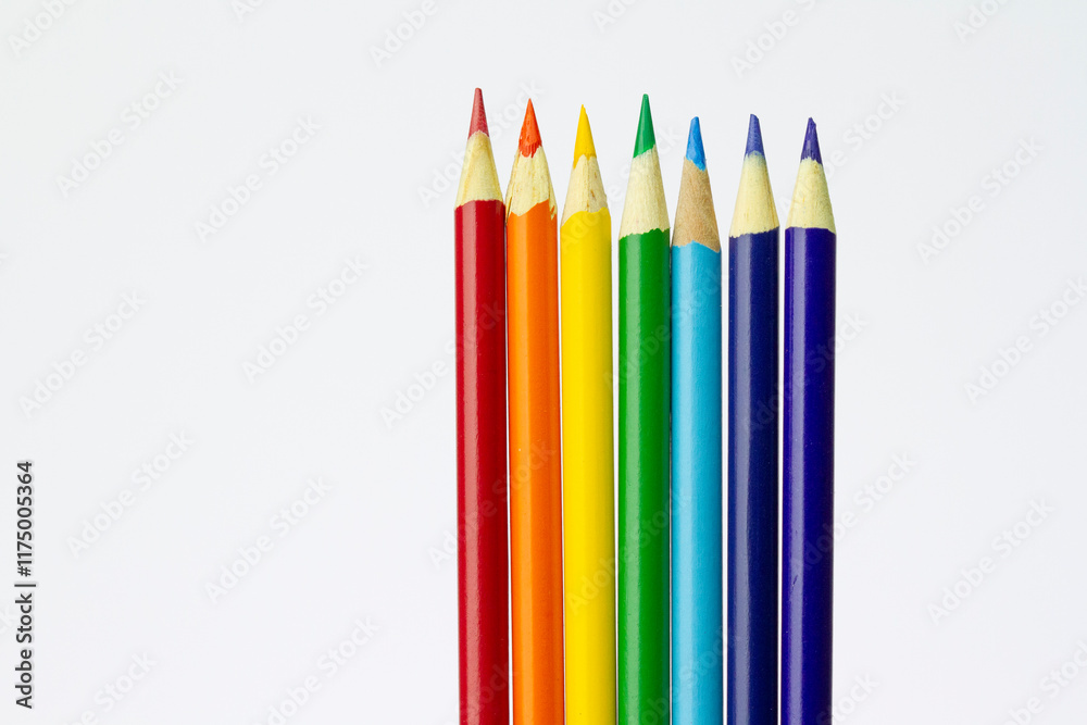 Rainbow coloured arrangement of sharpened pencils in a row on white background.