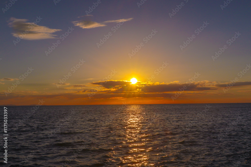Obraz premium Landscape A stunning sunset paints the sky with vibrant hues of orange and purple as the sun dips below the horizon, reflecting its warmth on the calm ocean. (3)