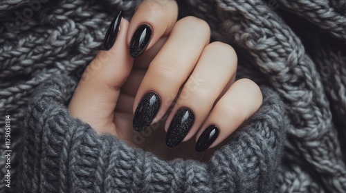 Elegant winter nails adorned with black crackle crystal necklaces on a cozy gray knitted backdrop in a minimal flat lay composition. photo