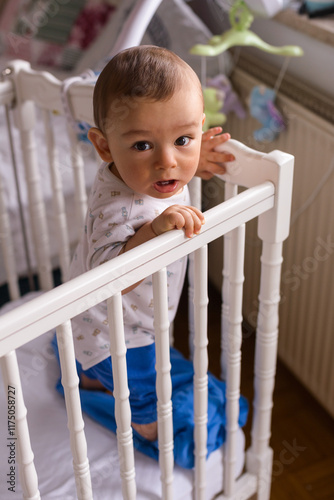 baby in a white baby cot standing