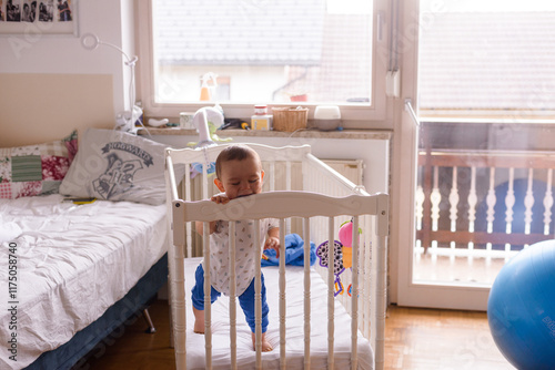 baby in a white baby cot standing