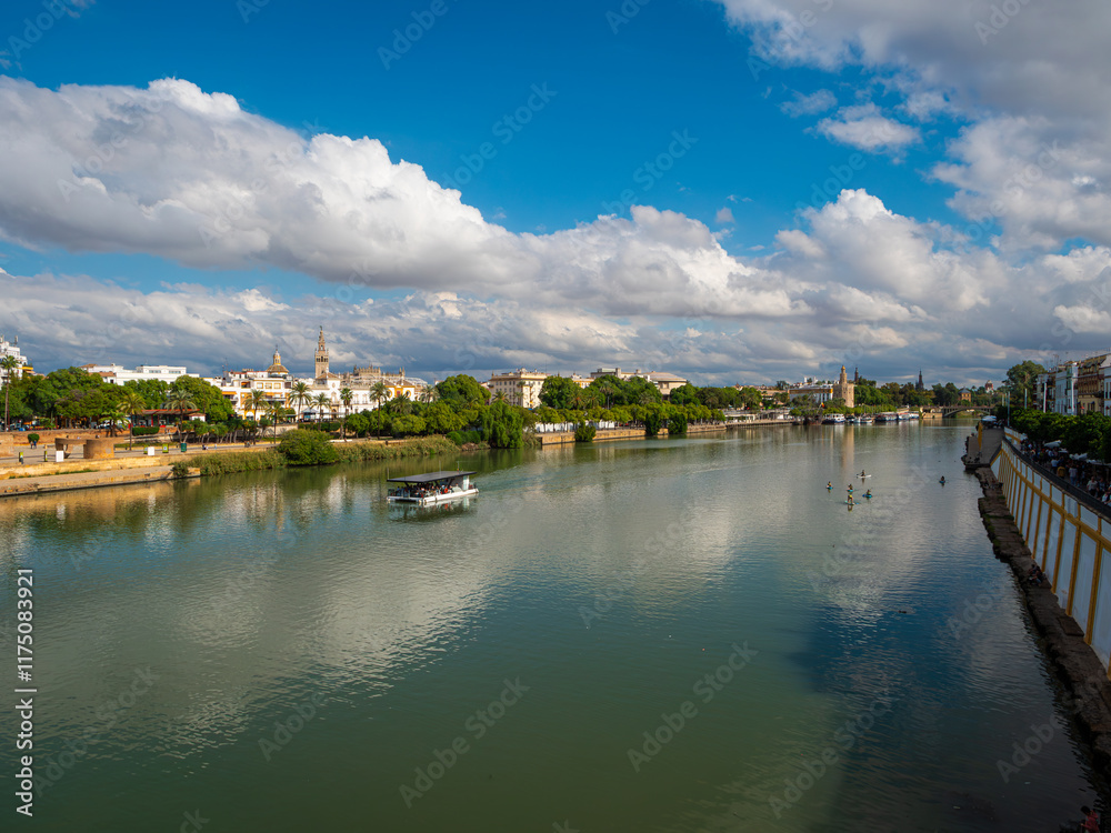 Naklejka premium The Canal de Alfonso X111 in Seville, Spain from the Puente de Triana bridge looking towards the Cathedral and La Giralda belltower. Space for text.