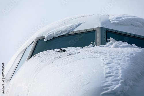 Snow covered cockpit of passenger airplane before de-icing process. Winter day at airport..
