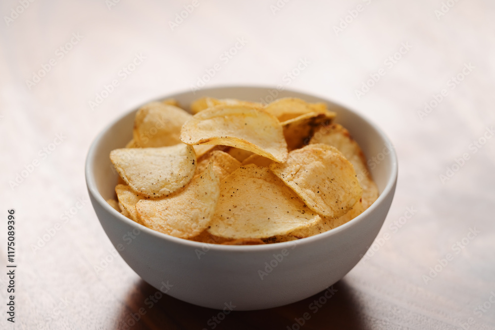 White bowl with organic potato chips sprinkled with fresh ground black pepper on wood background White bowl with organic potato chips sprinkled with fresh ground black pepper on wood background