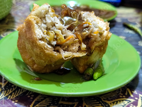 Tahu Isi or Tahu Brontak is an Indonesian food made from fried tofu with several types of vegetables including cabbage, mustard greens, bean sprouts and carrots. Served with chili on a green plate. photo