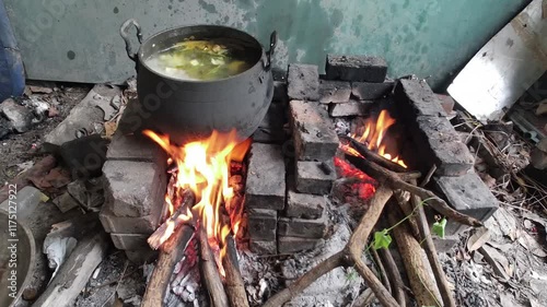Traditional cooking stove with raw materials using dry wood and bamboo. metal for heating water, cooking or boiling over a fire in a rustic wood stove. Concept, winter, cold, cozy, vintage,old kitchen