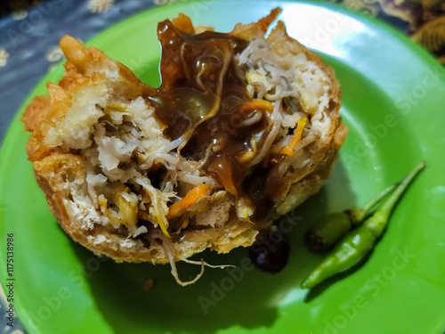 Tahu Isi or Tahu Brontak is an Indonesian food made from fried tofu with several types of vegetables including cabbage, mustard greens, bean sprouts and carrots. Served with chili on a green plate. photo