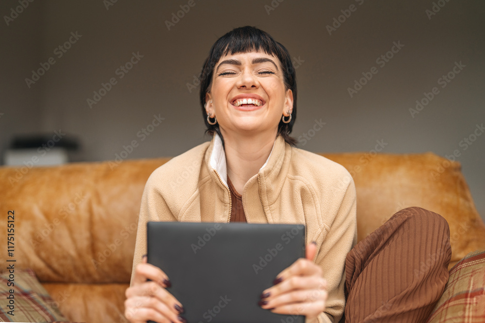 Woman enjoying a moment of joy while using a tablet at home on a cozy couch Woman enjoying a moment of joy while using a tablet at home on a cozy couch