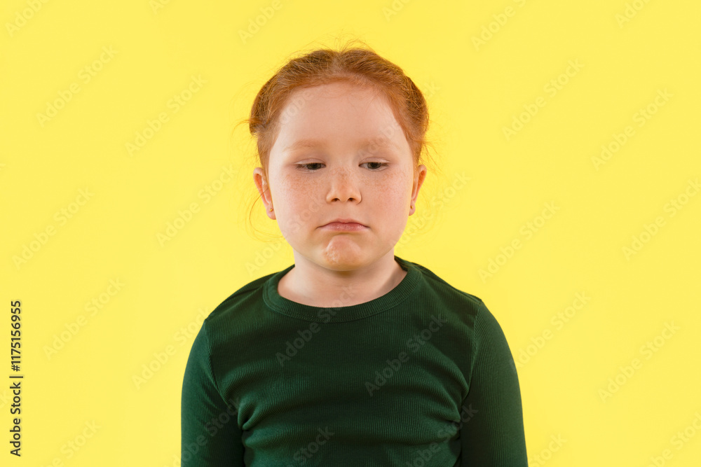 Young girl with red hair expressing a thoughtful mood against a bright yellow background Young girl with red hair expressing a thoughtful mood against a bright yellow background