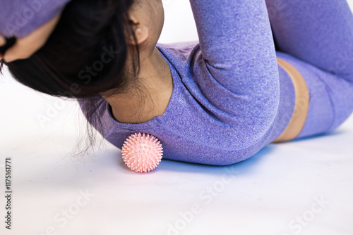 Athletic slim woman doing thigh self-massage with a massage ball indoors. Self-isolating massage photo