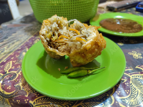 Tahu Isi or Tahu Brontak is an Indonesian food made from fried tofu with several types of vegetables including cabbage, mustard greens, bean sprouts and carrots. Served with chili on a green plate. photo