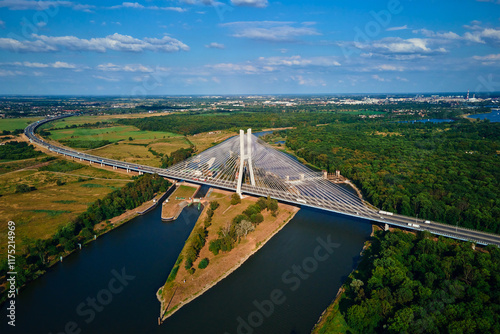 Obraz na płótnie Cable stayed bridge over river surrounded by lush green forest. Redzinski bridge over Odra river with cars driving on highway in Wroclaw, Poland w salonie