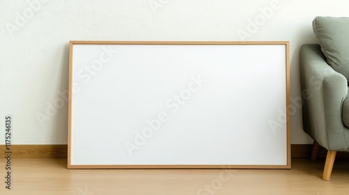 Large blank wooden frame leaning against a light green sofa in a minimalist room.