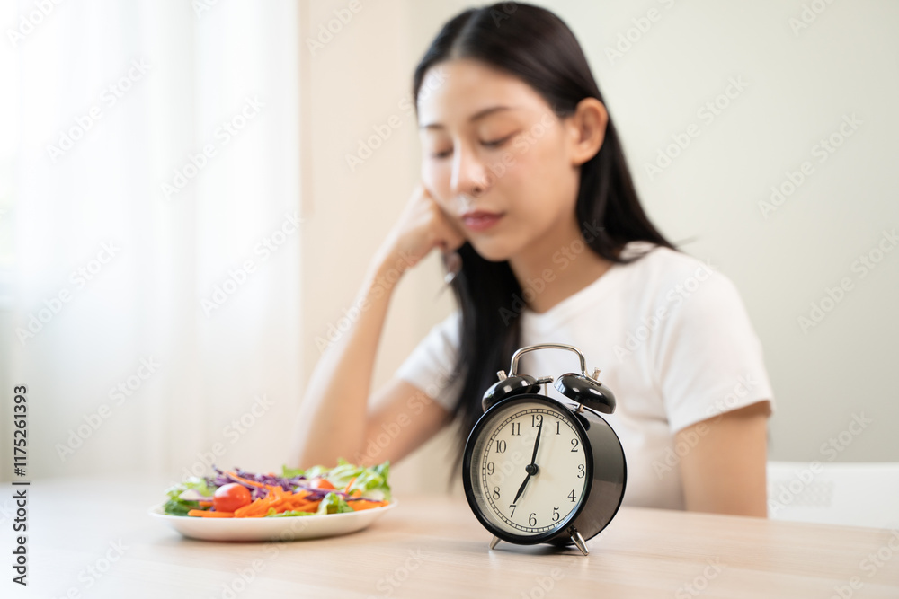 Intermittent fasting with clock, close up young woman, girl diet, waiting time to eat ketogenic low carb, green vegetable salad on plate. Eat food healthy first meal on brunch, lunch on table at home. Intermittent fasting with clock, close up young woman, girl diet, waiting time to eat ketogenic low carb, green vegetable salad on plate. Eat food healthy first meal on brunch, lunch on table at home.