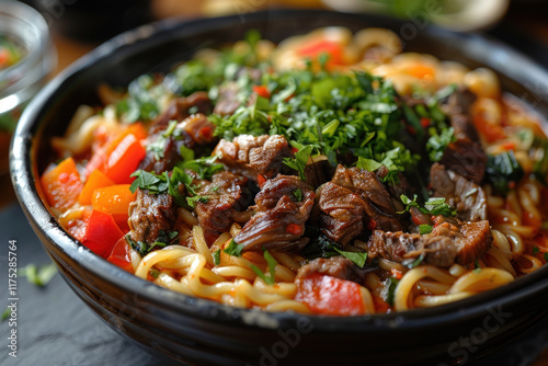 fried noodles with vegetables and beef in a black bowl. ,.      photo