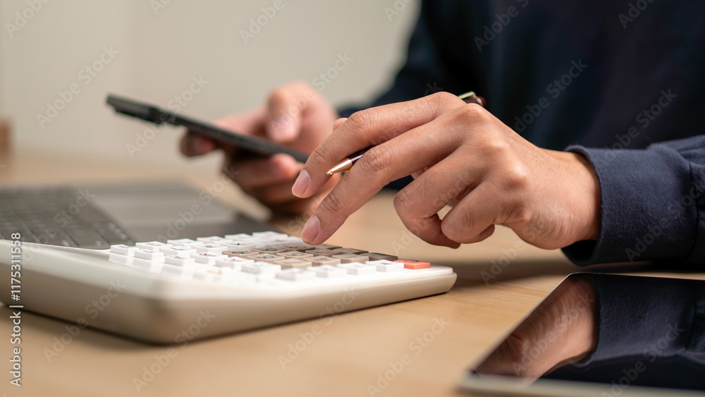 A close-up of a person's hands working with a calculator, smartphone, and laptop on a desk. financial management, budgeting, and productivity in a professional workspace.