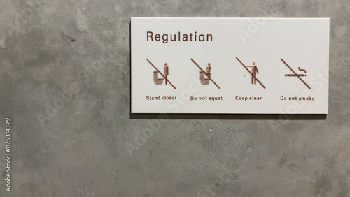 The warning sign on the toilet saying stand closer, do not squat, keep clean, and do not smoke on the toilet WC bathroom.