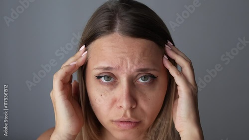 Wallpaper Mural Young caucasian woman touching the forehead showing active facial expressions on her face by raising and lowering her eyebrows on a dark grey background. Wrinkling the forehead. Skin care Torontodigital.ca