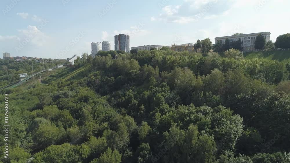Lush green hillside with a city in the distance. The city is made up of tall buildings and is surrounded by trees. The scene is peaceful and serene, with the city in the background. Nizhniy Novgorod Lush green hillside with a city in the distance. The city is made up of tall buildings and is surrounded by trees. The scene is peaceful and serene, with the city in the background. Nizhniy Novgorod