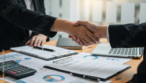 A professional handshake over financial documents, symbolizing business agreement, partnership, and collaboration.