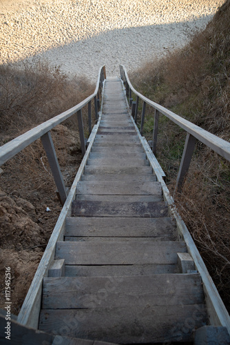 A high cliff of the coast with a long wooden staircase leading to a wild beach. photo