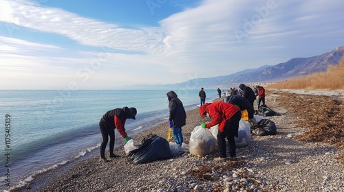 Fototapeta Naklejka Na Ścianę i Meble -  Volunteers cleaning a rocky beach by collecting trash into bags on a clear day, promoting environmental conservation and teamwork