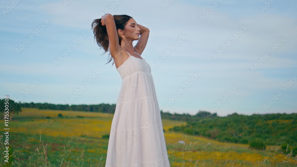 Relaxed woman standing farmland at morning. Smiling beautiful lady touching hair Relaxed woman standing farmland at morning. Smiling beautiful lady touching hair