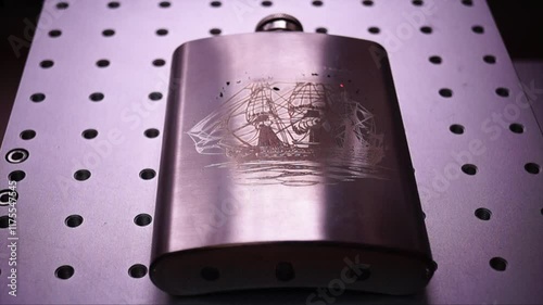 Engraved Metal Flask with Ship Design on Industrial Background photo