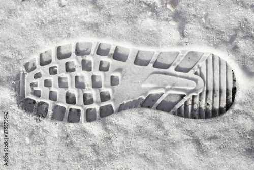 Shoe print on fresh snow. Detailed texture of a footprint in a frozen, white winter landscape. Mark of a human step in the cold outdoors. Icy ground background. Person imprint trace.