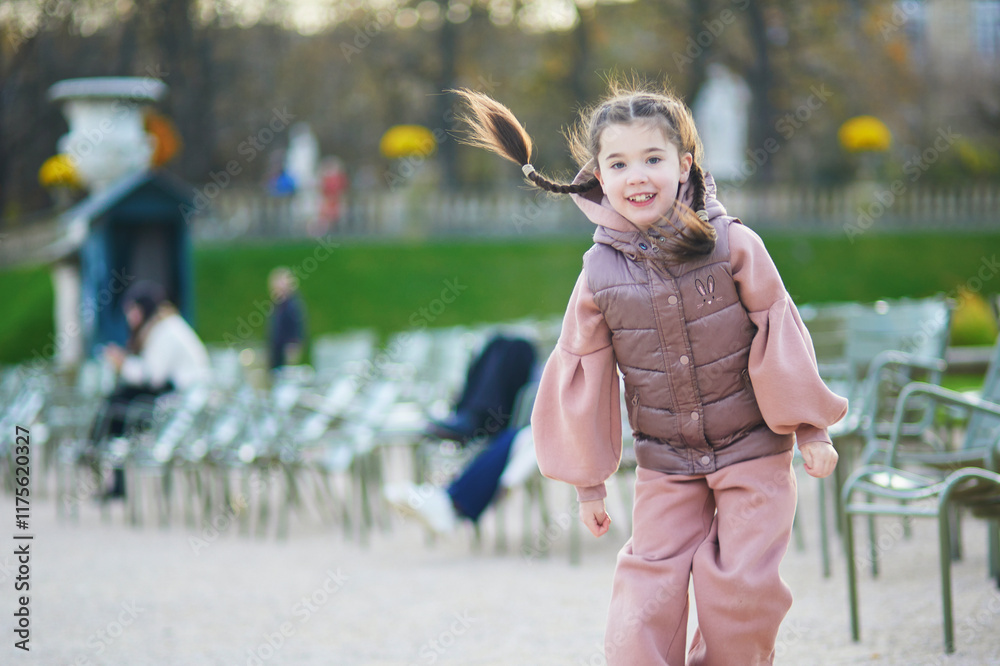 Fototapeta premium Adorable little girl having fun on a fall day in Luxembourg garden of Paris, France