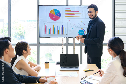 Businessman Giving Presentation Report to Business Team in the Conference Room, Shows Digital Information Graphics, Pie Charts about Company Growth on TV.