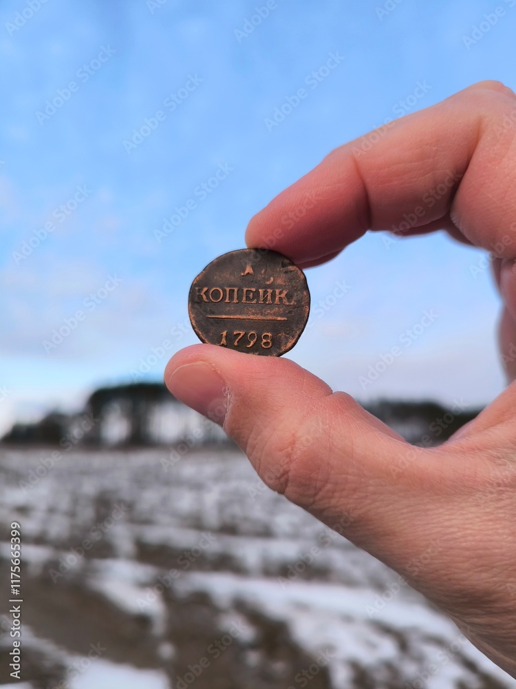 An old copper coin, a hand holding an ancient copper coin in a field. An ancient coin in your hands. Antique copper coin An old copper coin, a hand holding an ancient copper coin in a field. An ancient coin in your hands. Antique copper coin