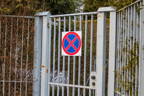 No parking sign on a metal gate surrounded by greenery photo