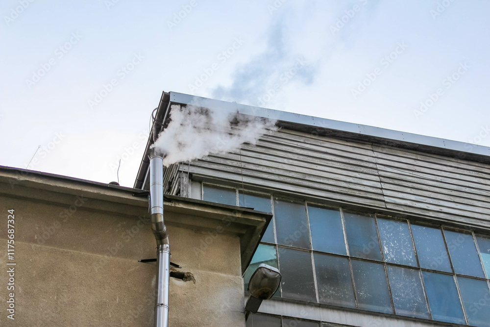 Smoke billowing from industrial building's exhaust pipe in clear sky Smoke billowing from industrial building's exhaust pipe in clear sky