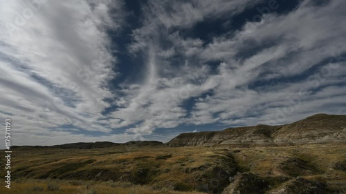 Time lapse of autumn clouds moving above a dry grassy prairie badlands setting
