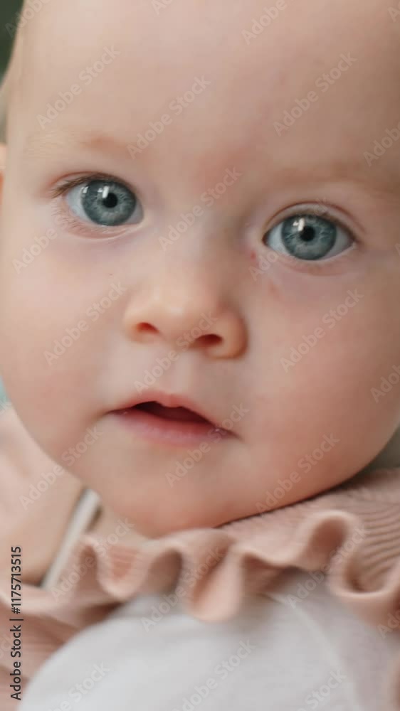 Vertical close up portrait of cute baby girl with blue eyes looking at camera Vertical close up portrait of cute baby girl with blue eyes looking at camera
