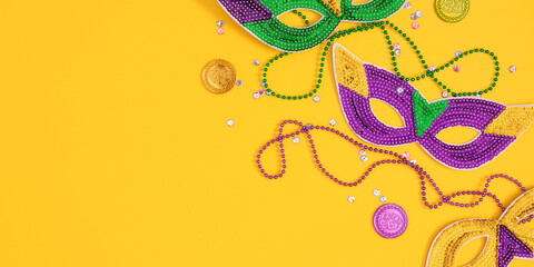 Top view of a beautiful composition of colorful masks, confetti, Mardi Gras decorations. Yellow Mardi Gras banner. Mardi gras holiday background