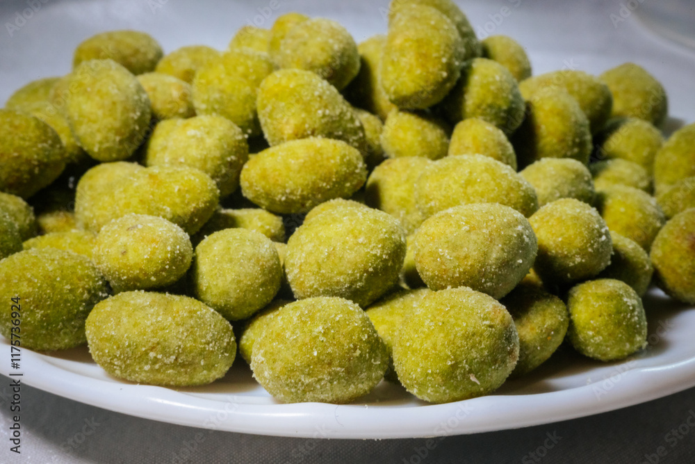 A close-up view of bright yellow-green wasabi-flavored nuts coated in a fine powder, creating a spicy and crunchy snack. Blurred background for emphasis. A close-up view of bright yellow-green wasabi-flavored nuts coated in a fine powder, creating a spicy and crunchy snack. Blurred background for emphasis.